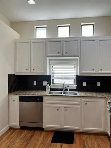 a view of empty room with wooden floor and kitchen
