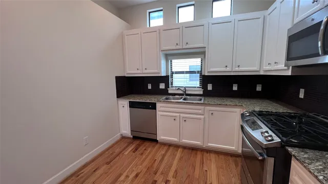 a kitchen with granite countertop a sink cabinets and stainless steel appliances