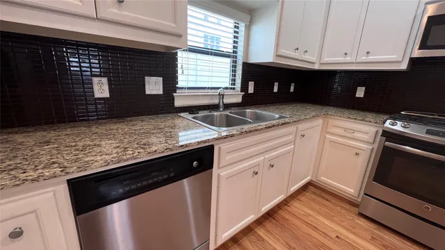 a kitchen with granite countertop a sink dishwasher stove and cabinets