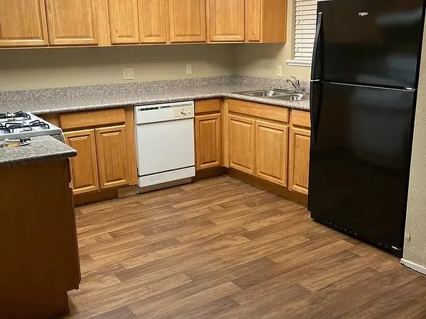 a kitchen with granite countertop a refrigerator sink and cabinets