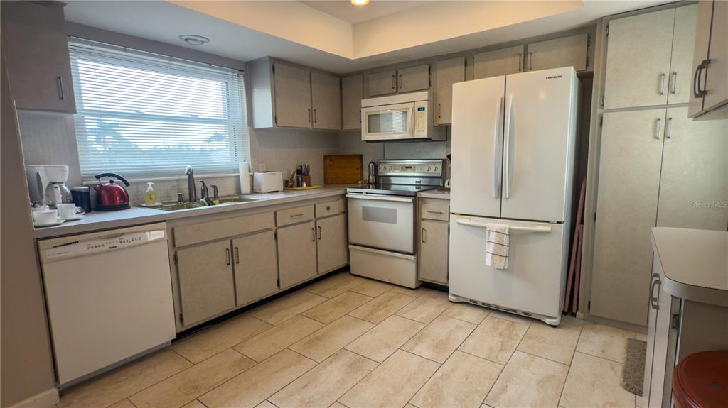 1900 Benjamin Franklin Drive, Unit 201BER Sarasota, FL 34236 - Photo 6 of 21 a kitchen with cabinets a refrigerator and a sink