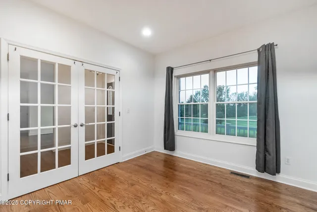 an empty room with wooden floor and windows