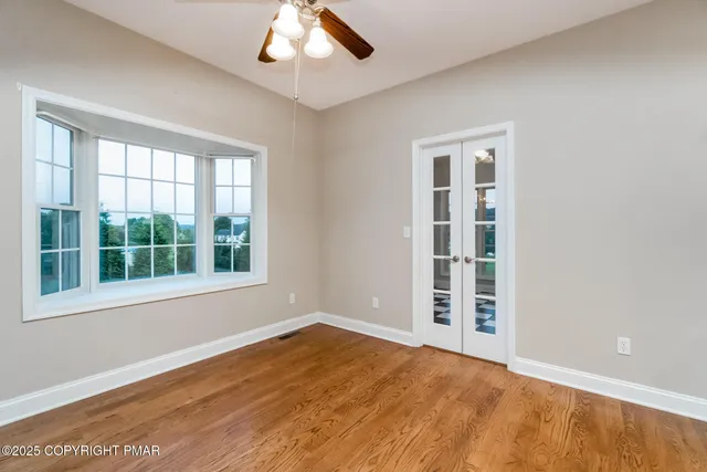 an empty room with wooden floor and windows