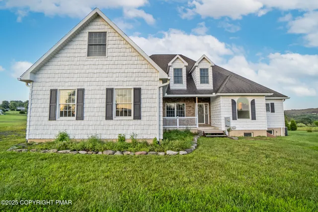 a view of a yard in front of a house with plants and large tree