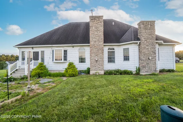 a front view of a house with a yard and potted plants