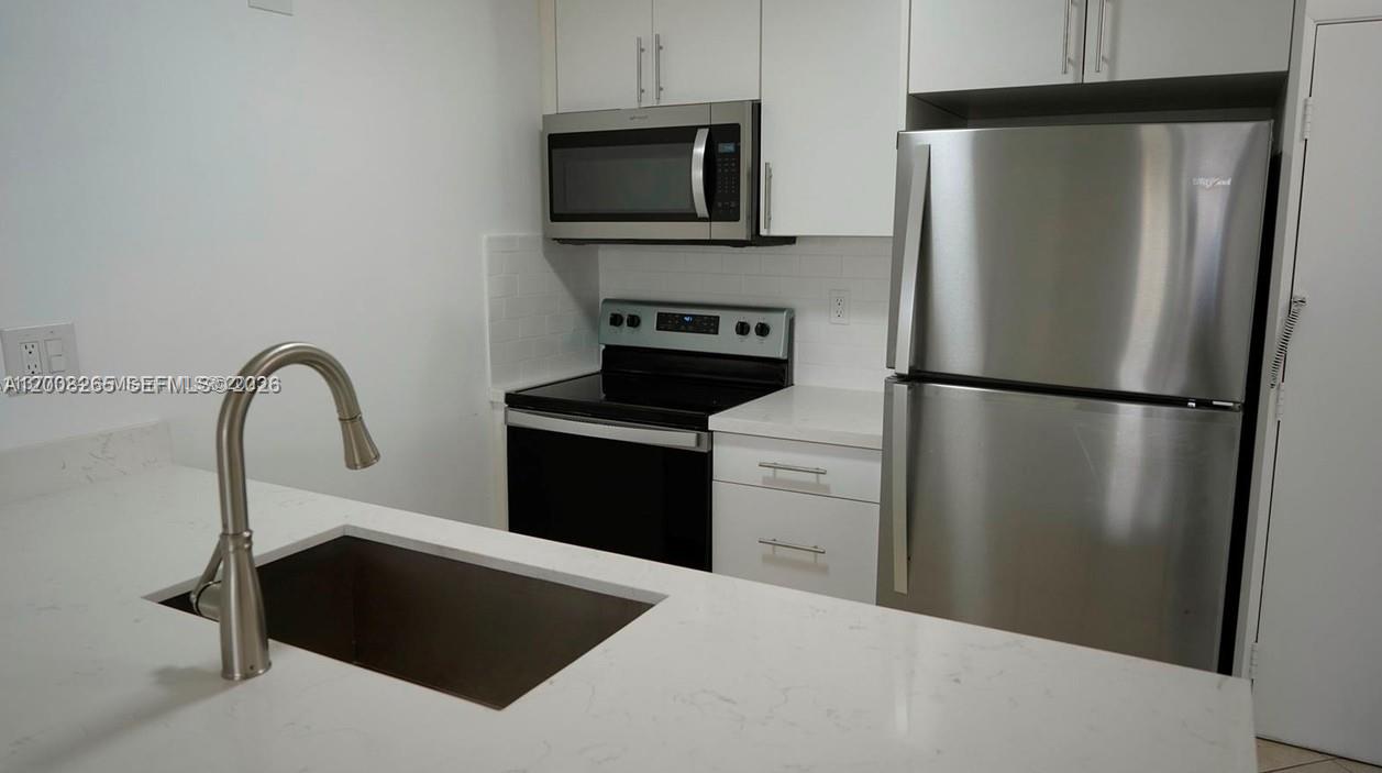 2771 Riverside Drive, Unit 405A Coral Springs, FL 33065 - Photo 4 of 19 a kitchen with a refrigerator and a stove top oven
