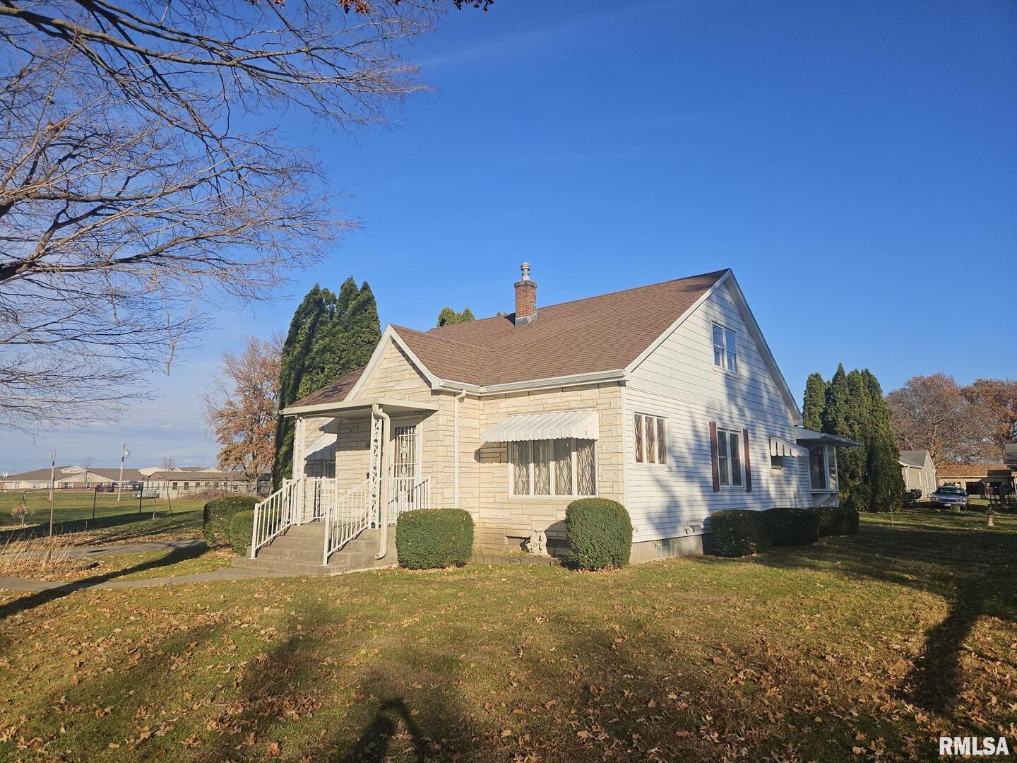 918 Seminary Street Wilton, IA 52778 - Photo 3 of 12 a view of a white house next to a yard with big trees