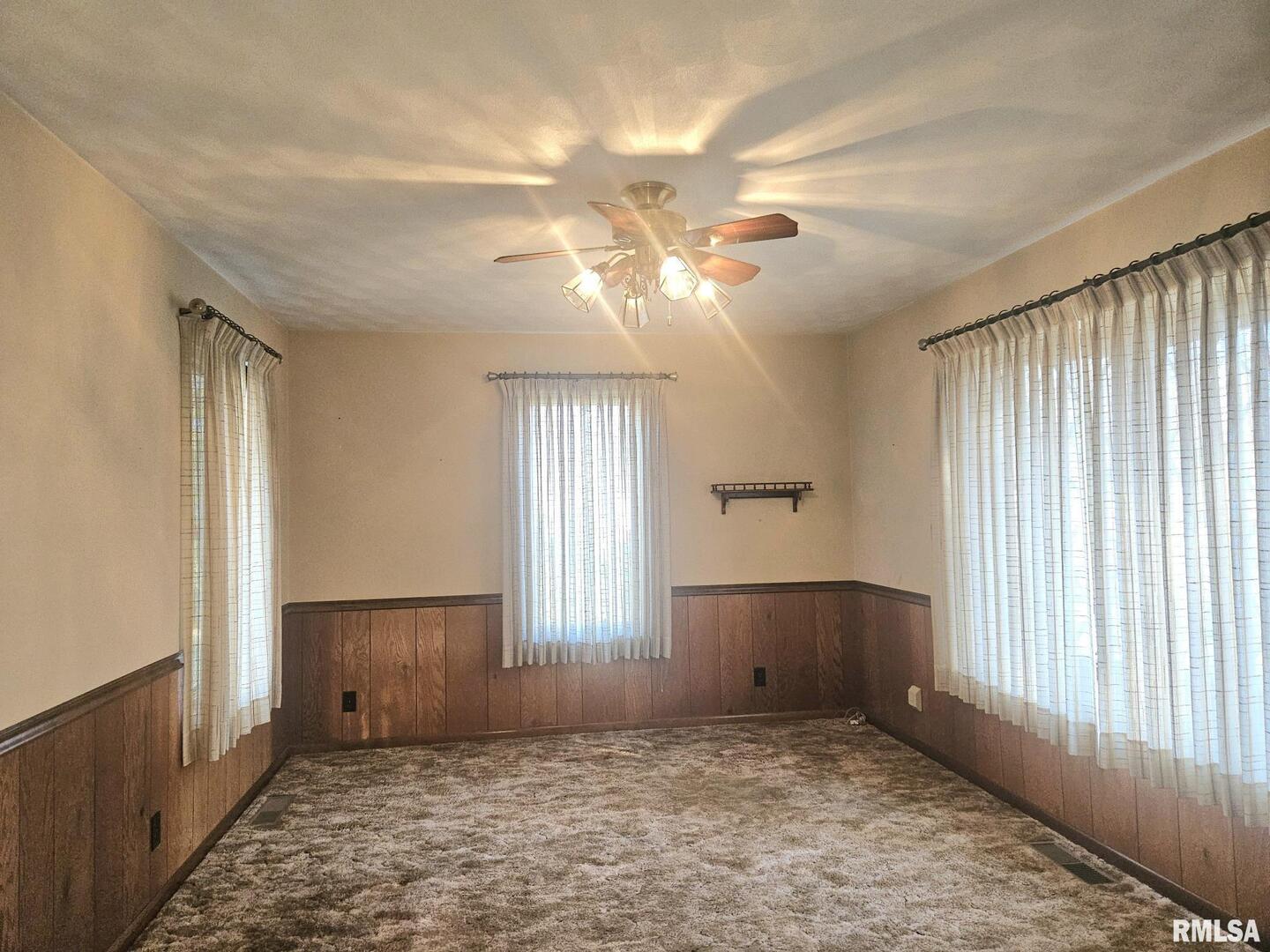 918 Seminary Street Wilton, IA 52778 - Photo 7 of 12 an empty room with windows and fan chandelier