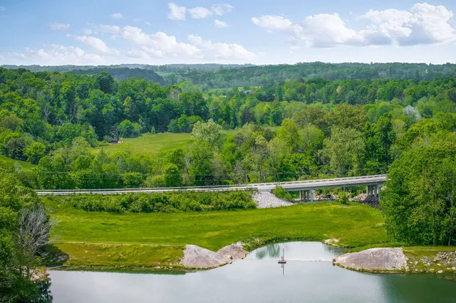 a view of a house next to a big yard and large trees