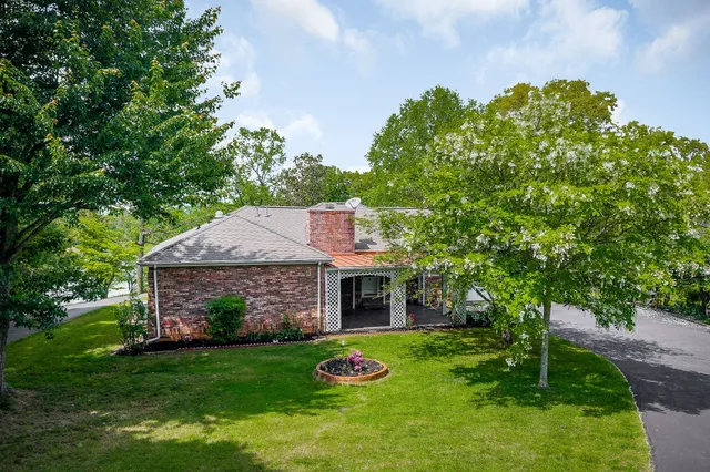 a front view of a house with a garden and trees