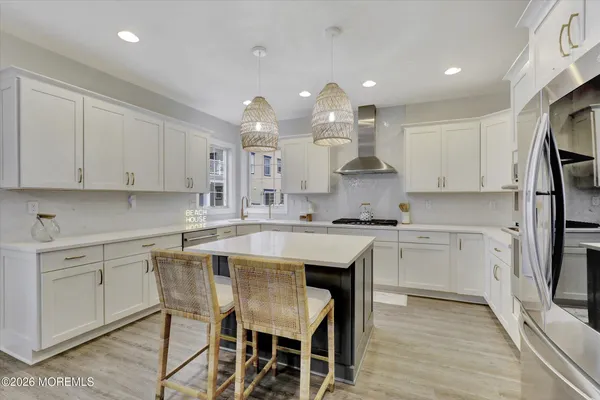 a kitchen with stainless steel appliances granite countertop a sink a stove and white cabinets with wooden floor