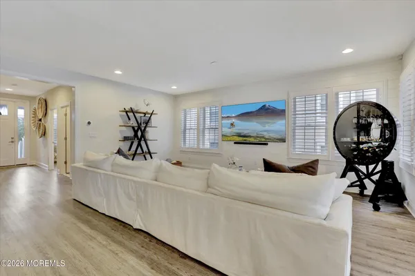 a living room with furniture and a large mirror next to a window
