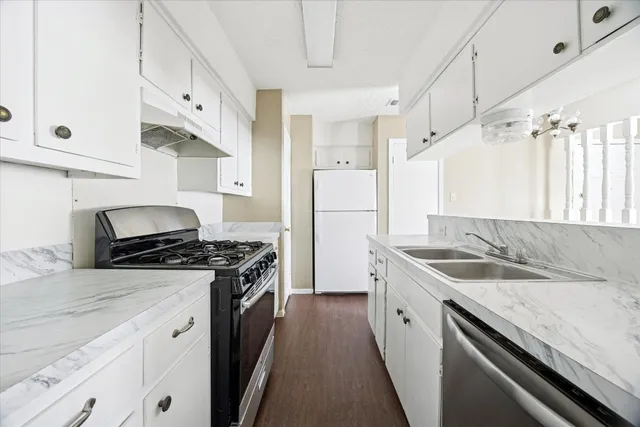 a kitchen with granite countertop a sink stove and refrigerator