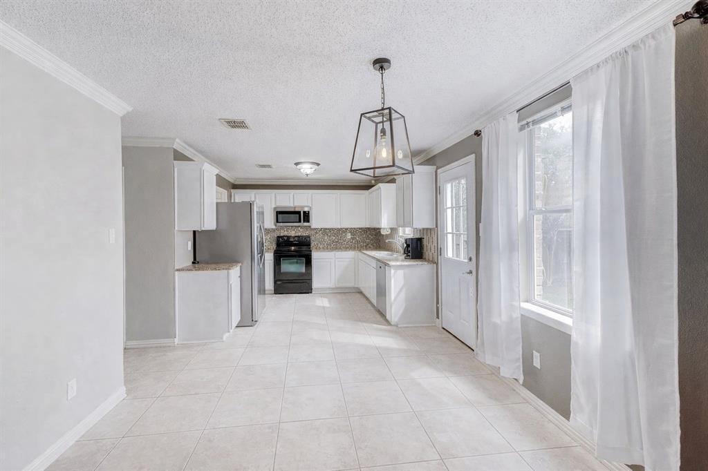 3601 McClintick Road McKinney, TX 75070 - Photo 9 of 24 a large white kitchen with white cabinets and stainless steel appliances