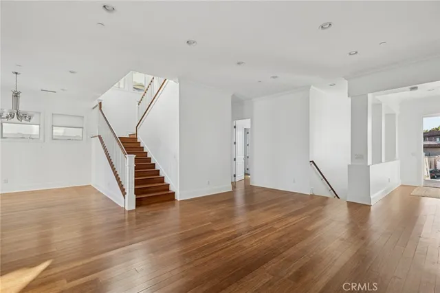 a view of an empty room with wooden floor and stairs
