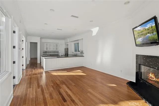 a view of a kitchen and an empty room with wooden floor and a kitchen