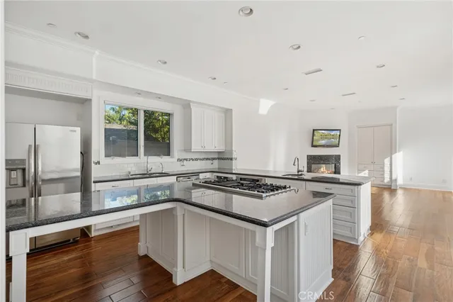a white kitchen with granite countertop a stove and a sink