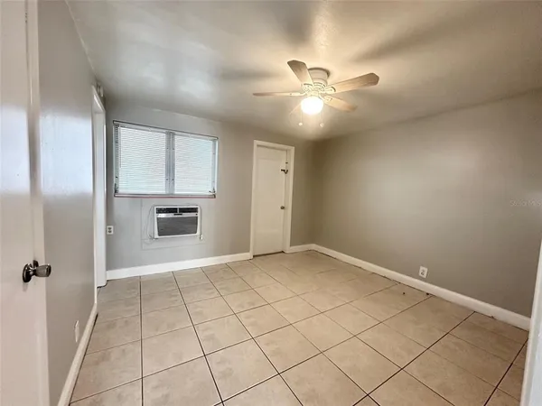 a view of an empty room with a ceiling fan and window
