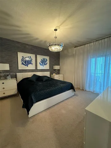 a bedroom with a bed chandelier and a window