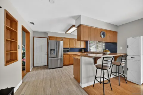 a kitchen with stainless steel appliances granite countertop a refrigerator a sink a stove and white cabinets with wooden floor