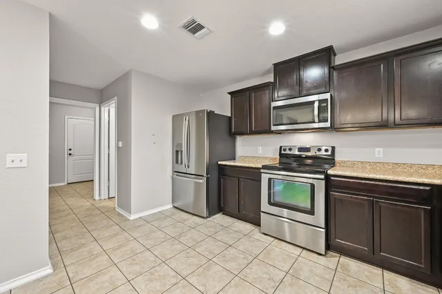 a kitchen with stainless steel appliances granite countertop a refrigerator and a stove top oven