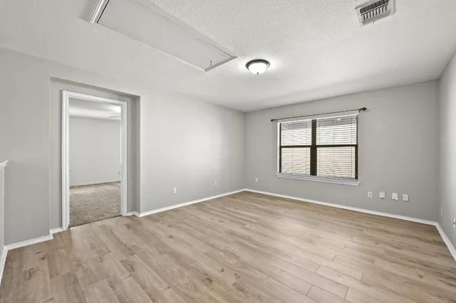 an empty room with wooden floor and windows