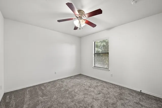 an empty room with ceiling fan and windows