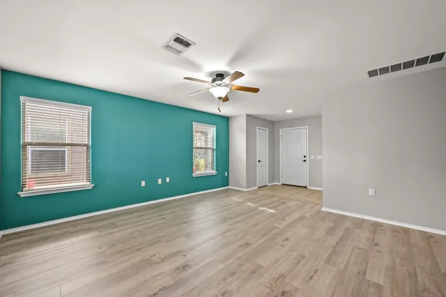 a view of an empty room with a window and a ceiling fan