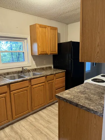 a kitchen with granite countertop wooden cabinets and a refrigerator