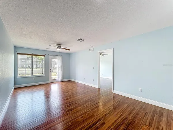 a view of a big room with wooden floor and windows
