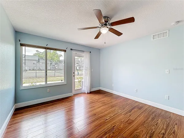 a view of empty room with wooden floor and ceiling fan