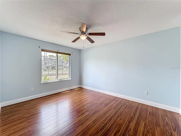 an empty room with wooden floor and a ceiling fan