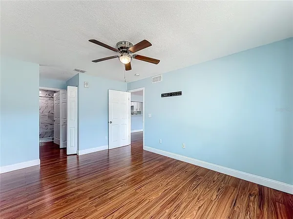 a view of empty room with wooden floor and fan