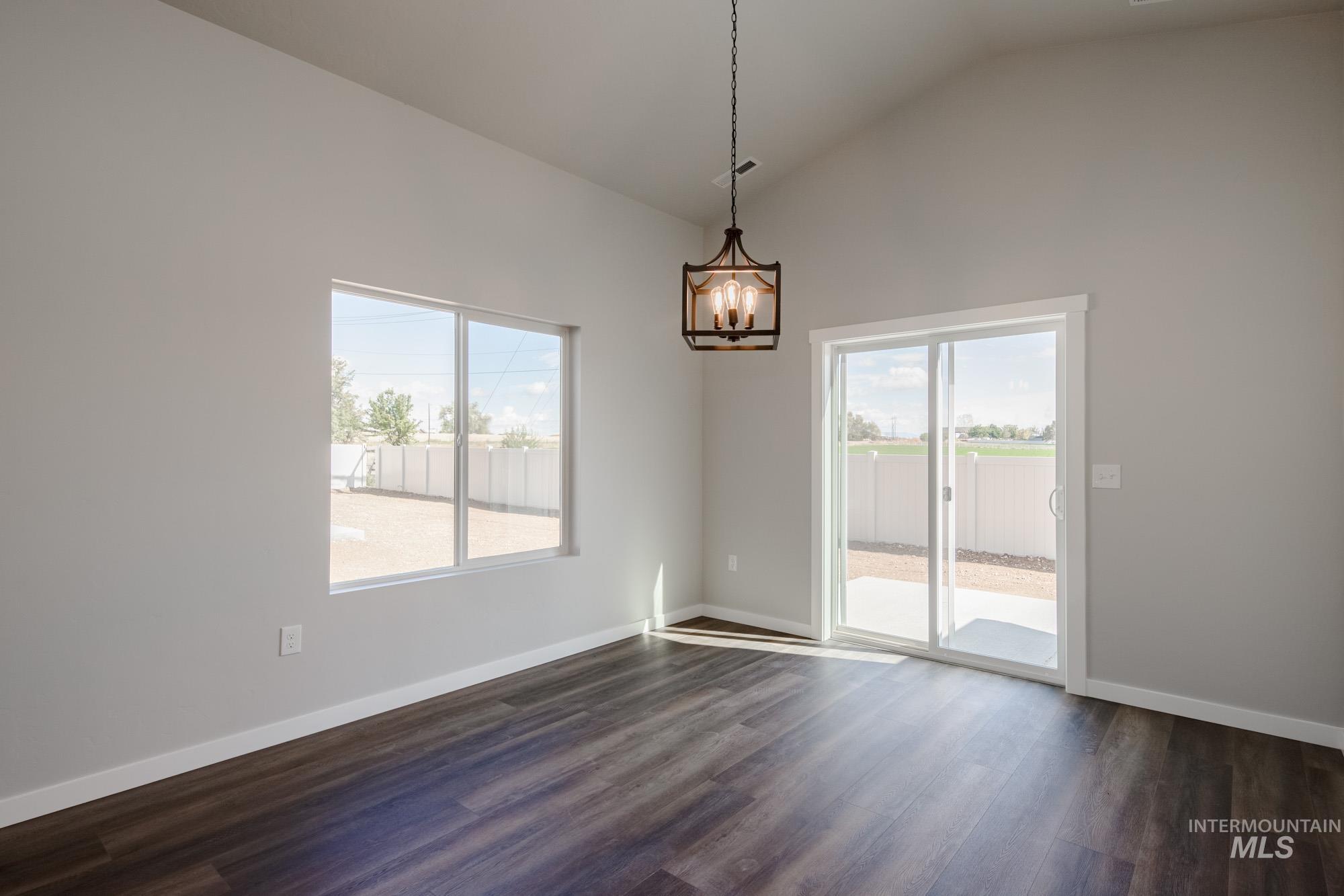 2940 North Schimigadoon Way Eagle, ID 83616 - Photo 9 of 21 Unfurnished room featuring dark wood-style floors, plenty of natural light, a chandelier, and high vaulted ceiling