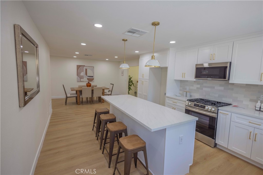 20530 Clark Street Perris, CA 92570 - Photo 10 of 25 a kitchen with stainless steel appliances granite countertop a stove a refrigerator a kitchen island a dining table and chairs with wooden floor