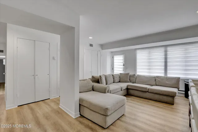 a living room with couches potted plants and a wooden floor
