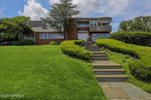 a front view of a house with garden and tree