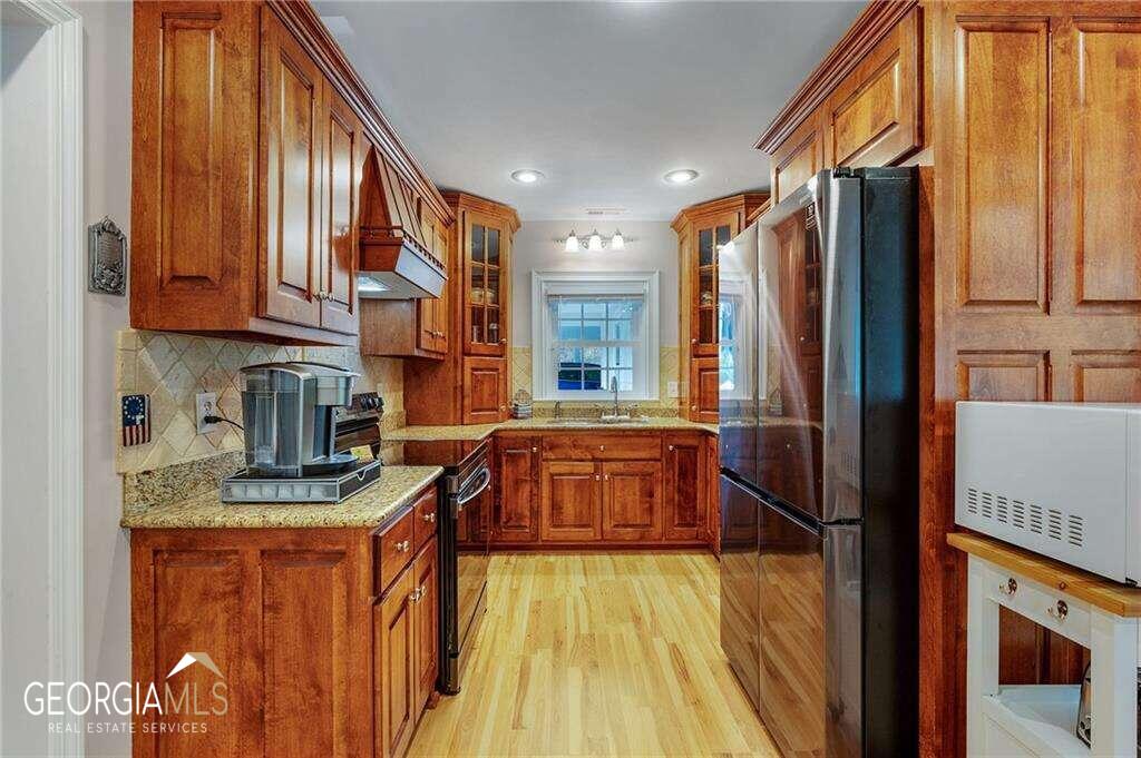 a kitchen with stainless steel appliances granite countertop a refrigerator a sink and wooden cabinets