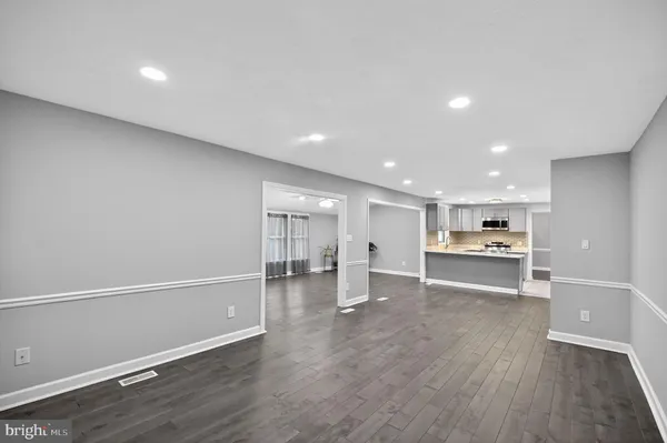 an empty room with wooden floor fireplace and windows