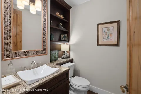 a bathroom with a granite countertop toilet sink and mirror
