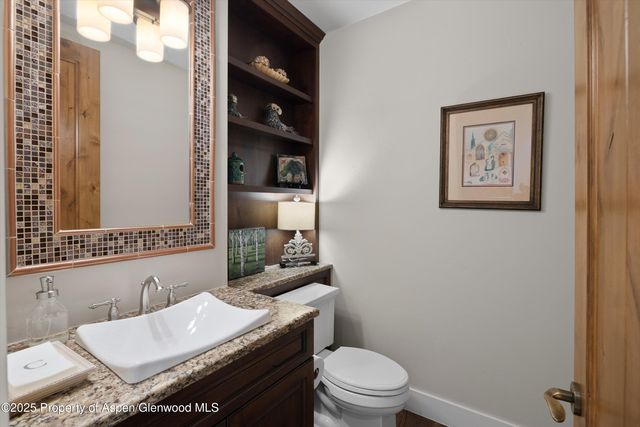 a bathroom with a granite countertop toilet sink and mirror