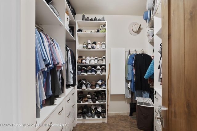 a view of walk in closet with clothes and shoes