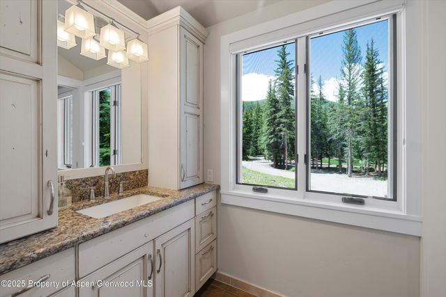 a bathroom with a granite countertop sink and a large mirror