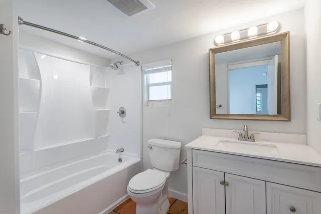 a bathroom with a granite countertop toilet a sink and a bathtub
