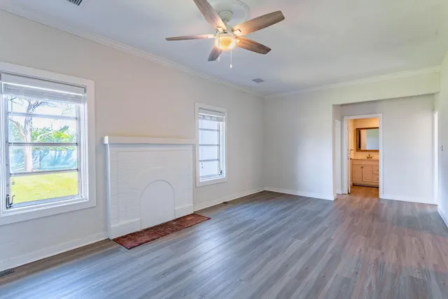 a view of an empty room with window and wooden floor