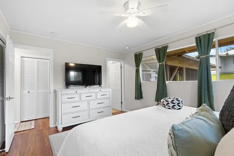 a bedroom with a large bed and a flat tv screen on dresser