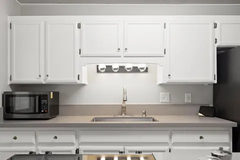 a kitchen with granite countertop white cabinets and stainless steel appliances