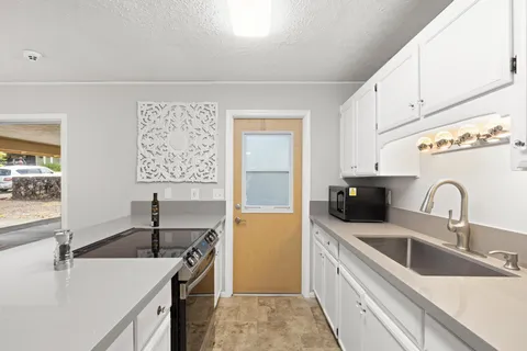 a kitchen with a sink and a stove top oven with wooden floor