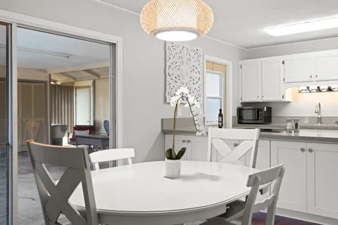 a kitchen with stainless steel appliances granite countertop a dining table chairs and a refrigerator