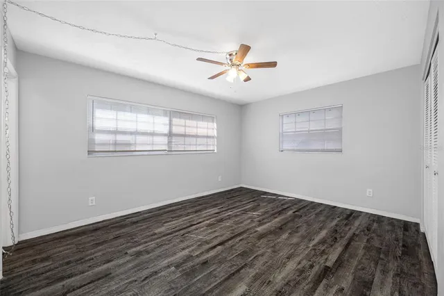 a view of empty room with wooden floor and fan